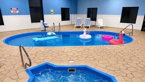 Una piscina interior con hidromasaje, sillas de descanso y juguetes inflables.