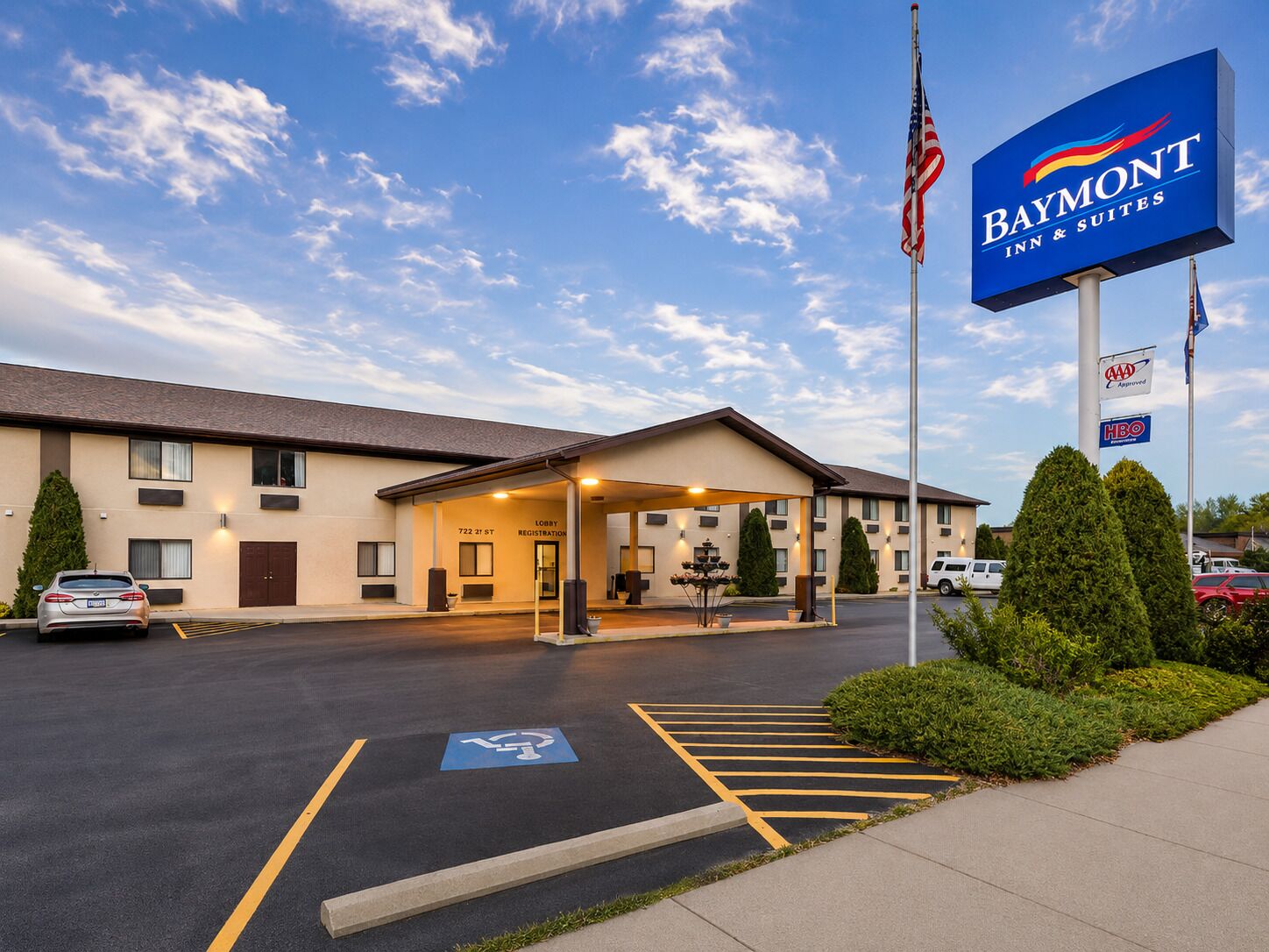 Een Baymont Inn & Suites met een parkeerplaats, een receptie en een Amerikaanse vlag.