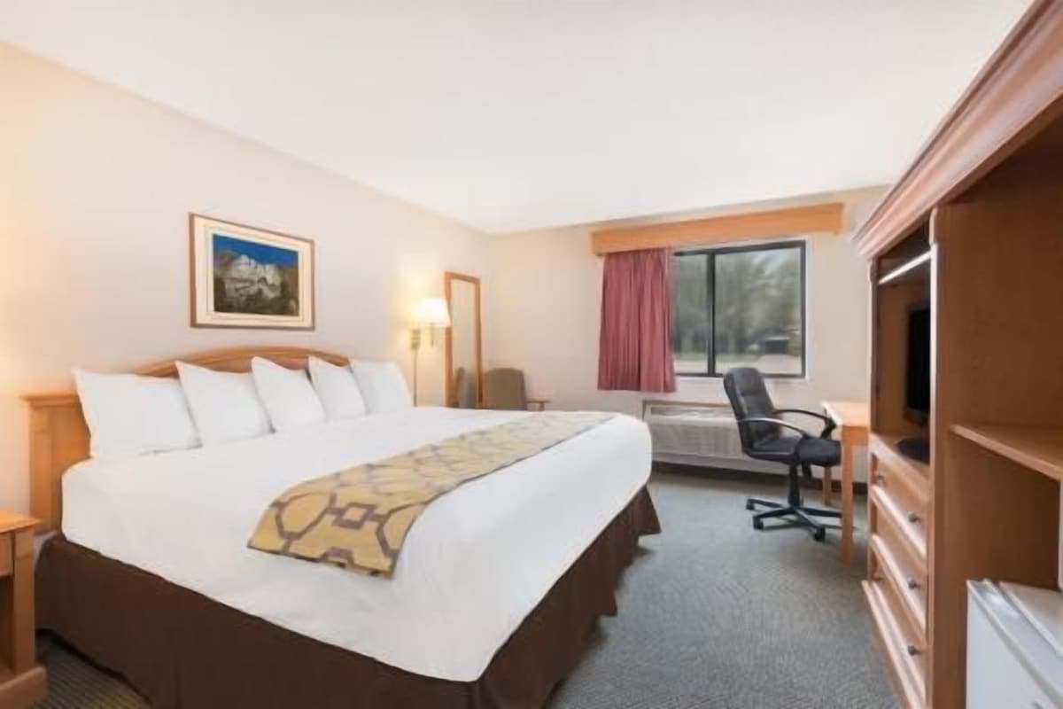 Una habitación de hotel con cama, escritorio, silla, televisión y ventana.