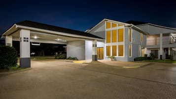 A modern two-story building with a covered garage and a well-lit entrance.