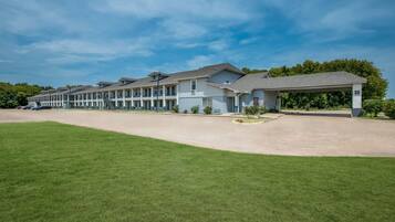 A multi-story motel with a covered parking area and a well-maintained lawn.