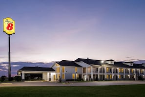A motel with a prominent 'Super 8' sign, featuring a modern two-story building with multiple rooms and a parking area.