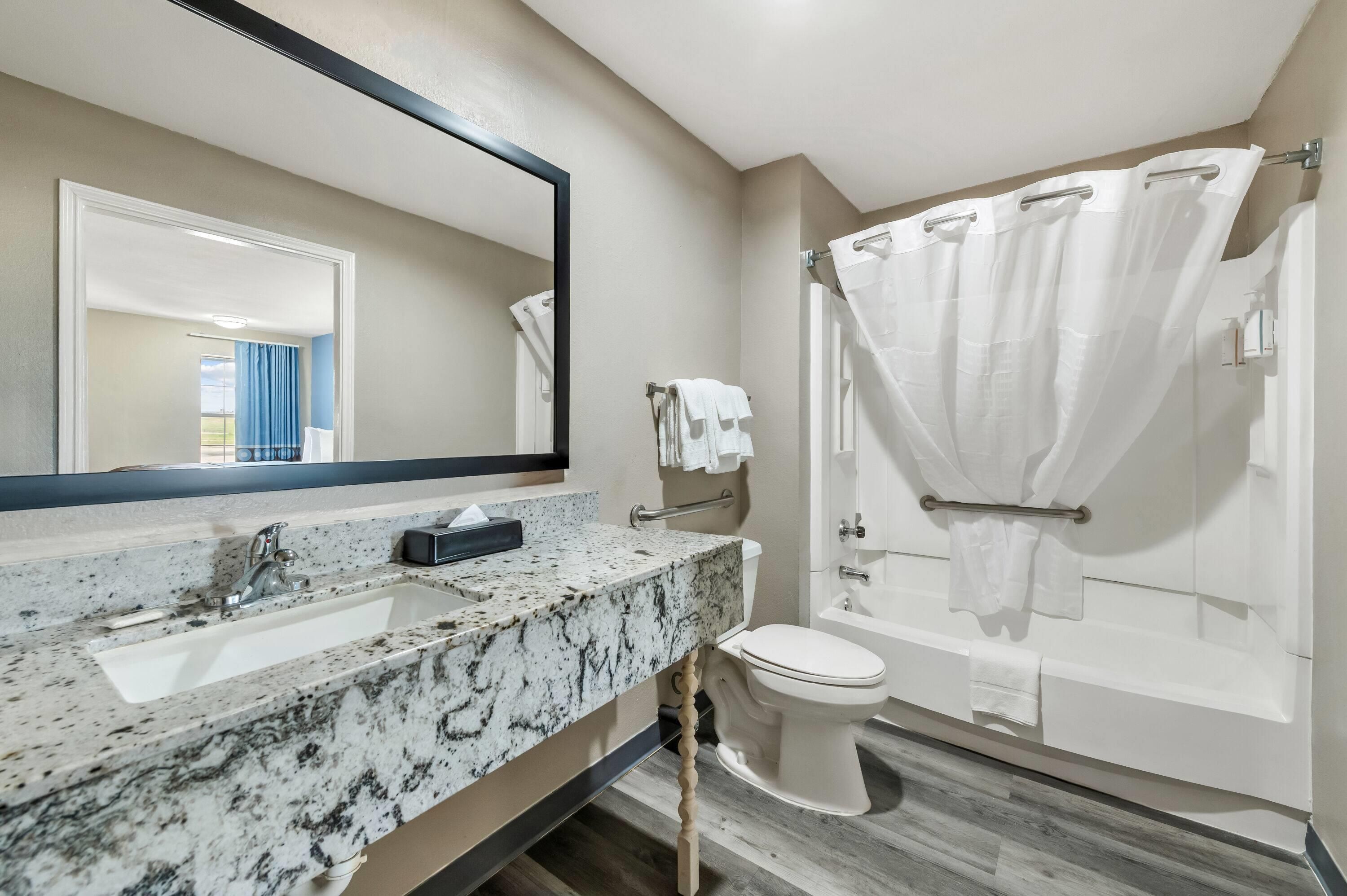 Un baño con lavamanos de mármol, inodoro y bañera con cortina de ducha.