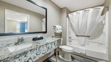 A bathroom with a marble sink, a toilet, and a bathtub with a shower curtain.