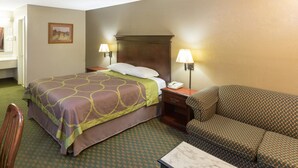 Una camera d'albergo con un letto, un comodino con una lampada, un divano e una sedia.