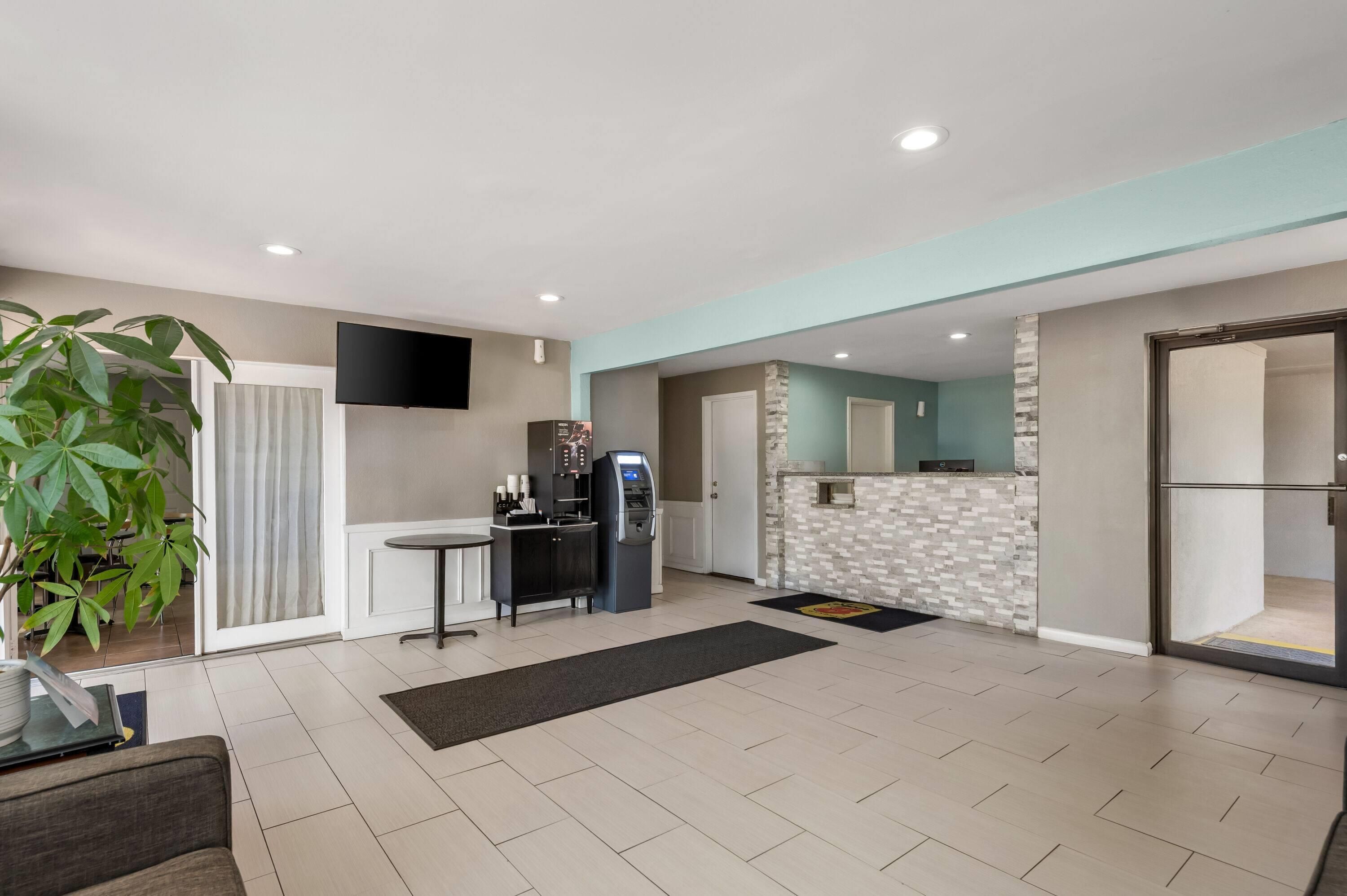 A modern living room with a flat-screen TV, a coffee machine, and a dining area with a table and chairs.