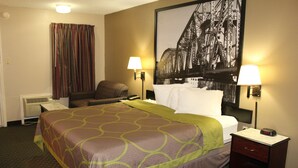 Camera d'albergo con un letto, una sedia, un comodino, una lampada, un riscaldatore a parete e un grande quadro con un ponte.