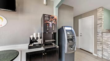 Een koffieautomaat met een Nescafe logo, een geldautomaat en een televisie aan de muur.