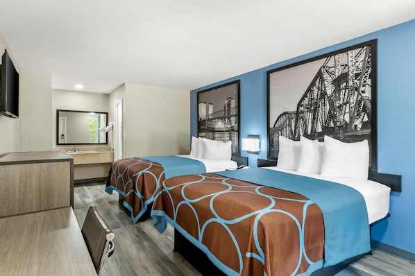 A hotel room with two beds, a desk, a mirror, and a large cityscape painting on the wall.