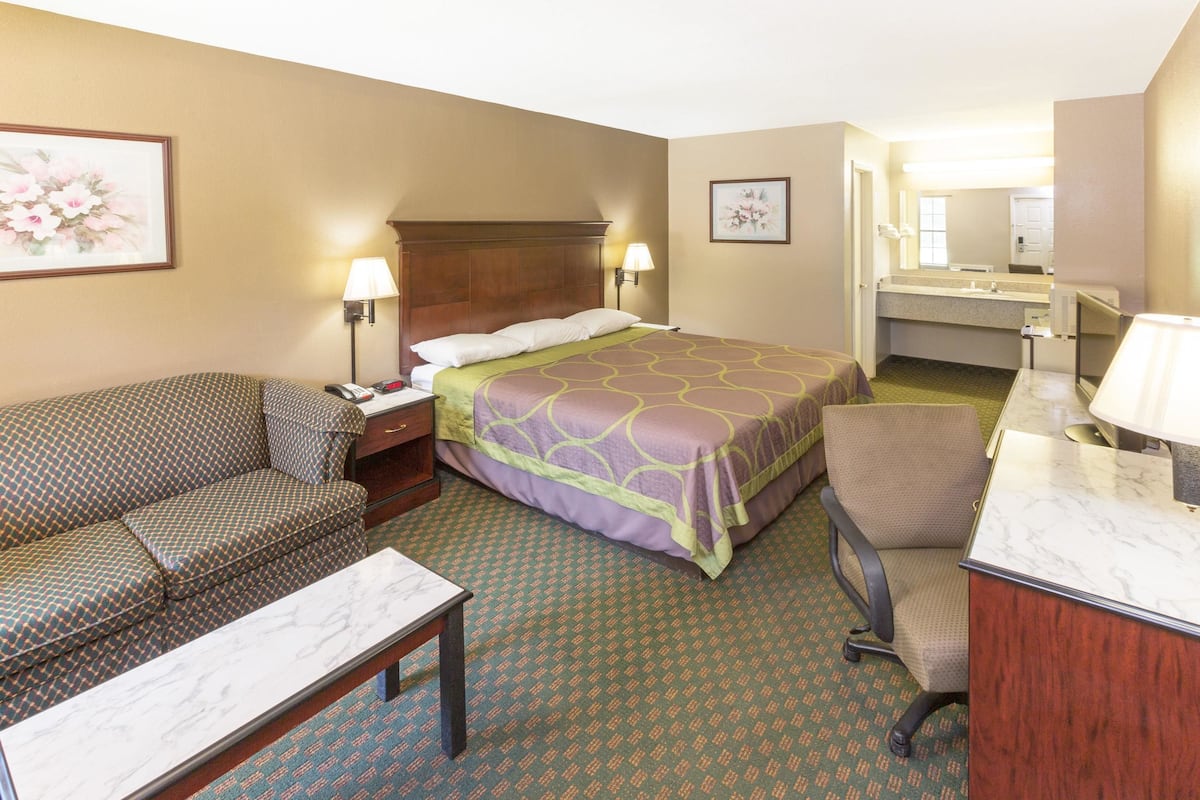 A hotel room with a bed, a sofa, a desk, and a bathroom.