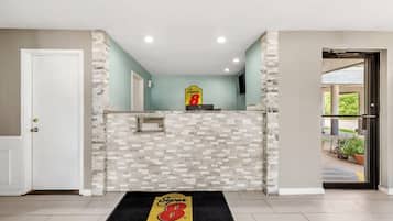 A reception area with a stone wall, a Super 8 by Wyndham logo rug, and a door leading to the outside.