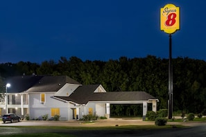 Um motel com um letreiro grande de 'Super 8', um edifício térreo com teto plano e área de estacionamento na frente.