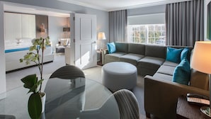 A modern hotel room with a bed, a sofa, a dining table, and a TV. - Westminster Hotel (Livingston)