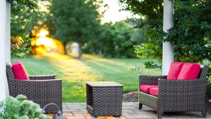 An outdoor patio area with wicker furniture and a small table. - Westminster Hotel (Livingston)