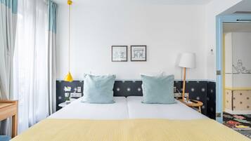 Une chambre d’hôtel avec un lit, deux oreillers, une table de chevet, une lampe et un mur orné de deux tableaux encadrés.