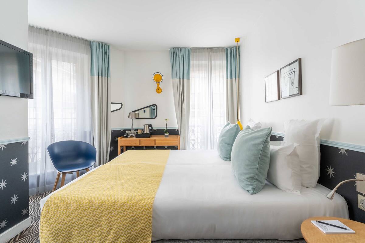A hotel room with a bed, a desk, a chair, and a TV.