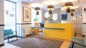 A modern kitchen with a yellow island, black pendant lights, and a patterned rug. - Hôtel Augustin - Astotel (Paris)