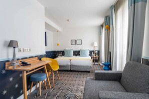 A modern hotel room with a bed, a desk, a chair, a sofa, and a small table. - Hôtel Augustin - Astotel (Paris)