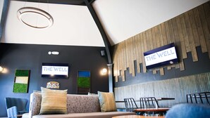 En modern inredning med en soffa, stolar och bord, en skylt med texten ”THE WELL” och en träpanel på väggen.