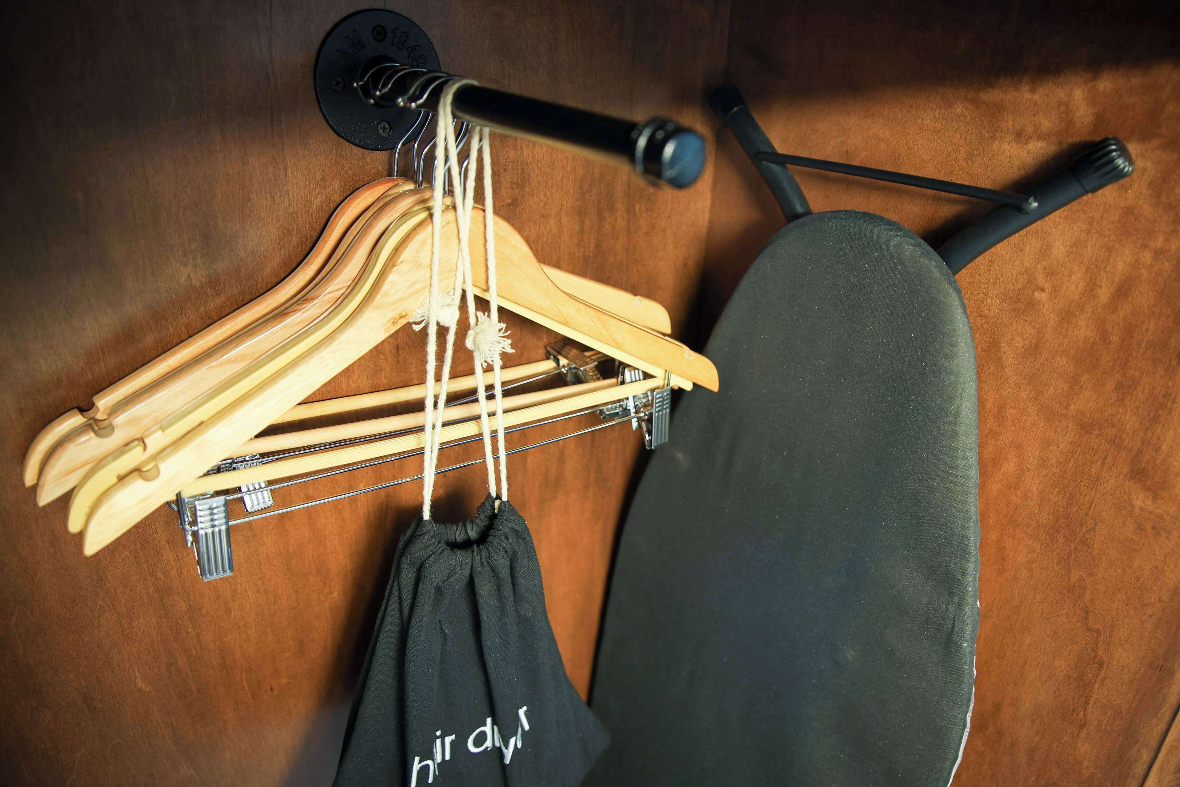 A wooden hanger rack with hangers and a black bag.