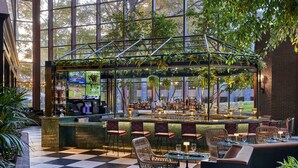 A bar area with a checkered floor, wicker chairs, and a bar counter with a view of the outdoors. - Omni Charlottesville Hotel (Charlottesville)