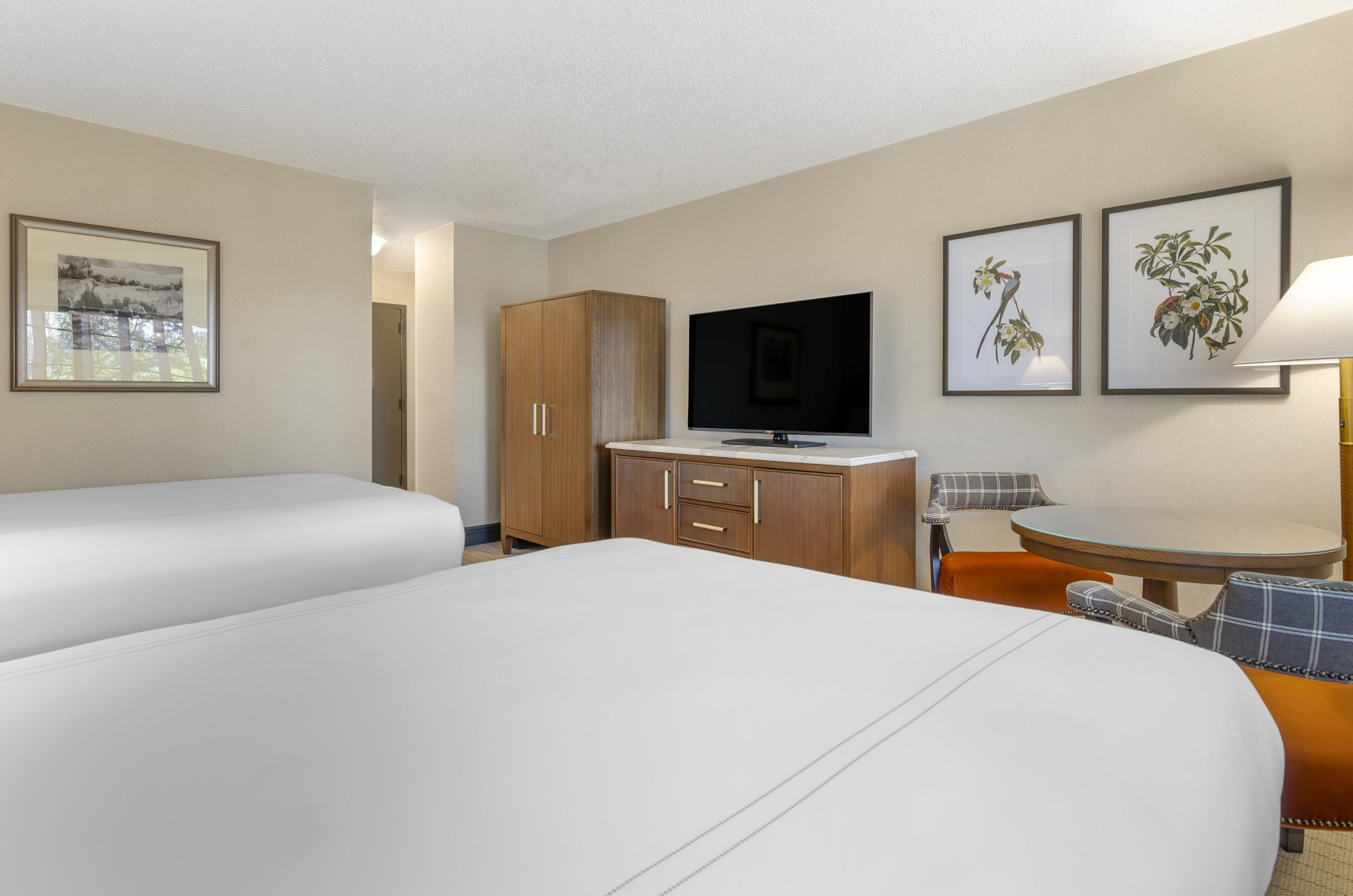 A hotel room with two beds, a TV, a desk, and a chair.