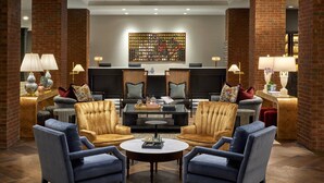 A lobby with a brick wall, two sofas, a coffee table, and a decorative wall piece. - Omni Charlottesville Hotel (Charlottesville)