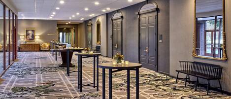 A hotel lobby with a patterned carpet, a reception desk, and a bench.