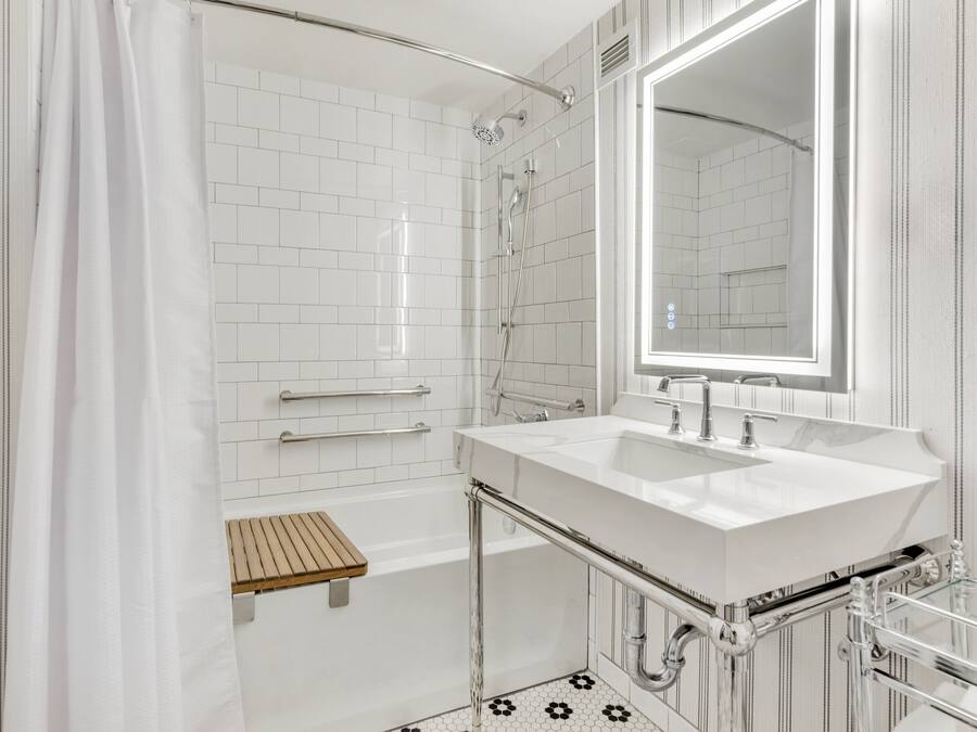A modern bathroom with a white tiled shower, a glass-enclosed bathtub, and a large mirror above a white sink.