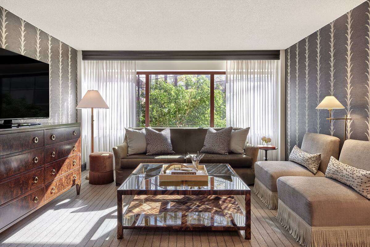 A living room with a sofa set, a coffee table, a TV, and a large window with curtains.