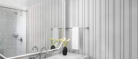A modern bathroom with a white marble sink, a large mirror, and vertical striped wallpaper.