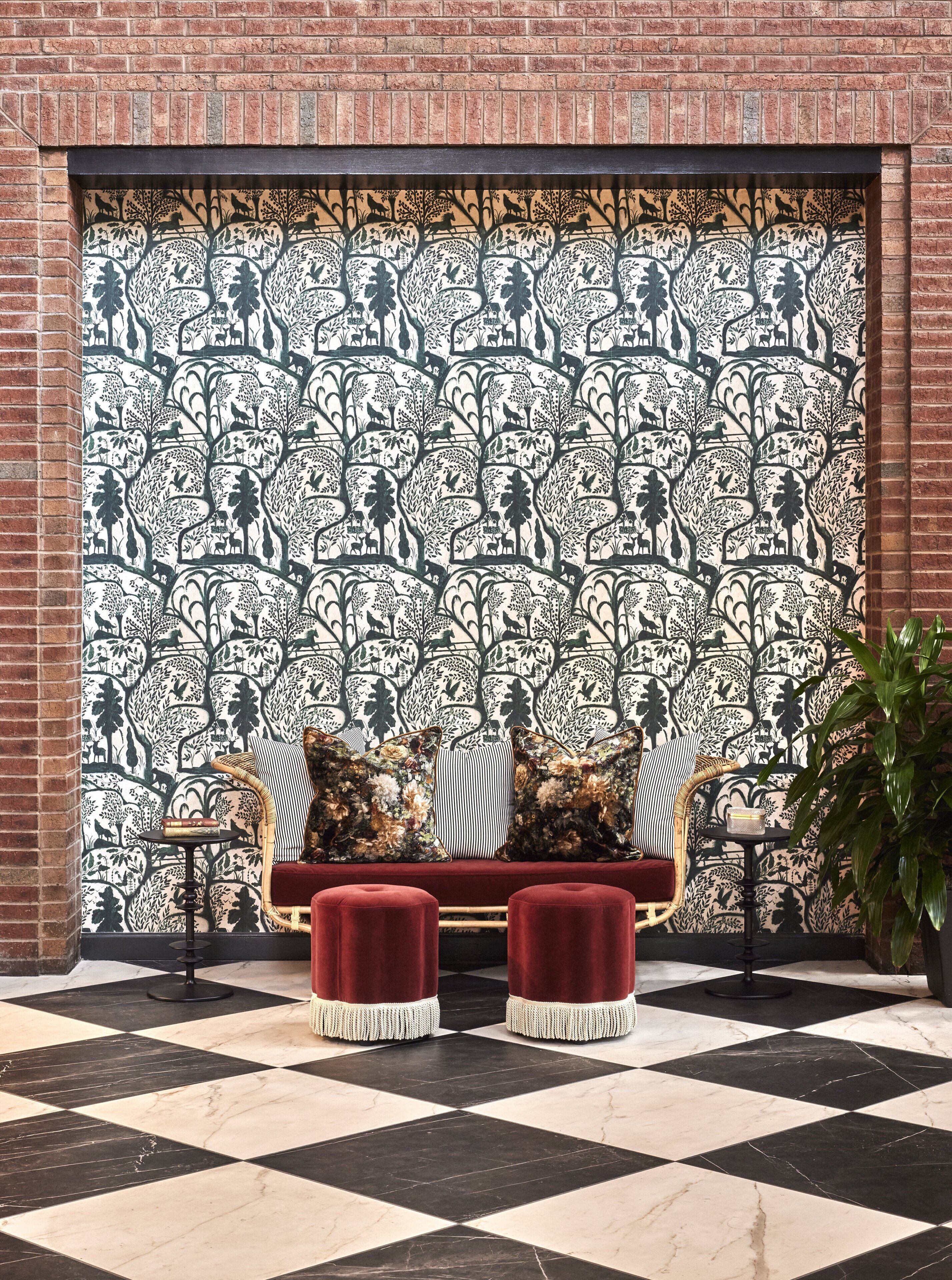 A checkered floor with a patterned wall, a wicker sofa with red cushions, and a small table.
