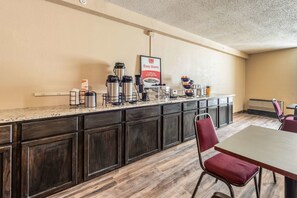 Una kitchenette con estación de café, un letrero que dice 'Easy Starts' y un comedor con mesa y sillas.