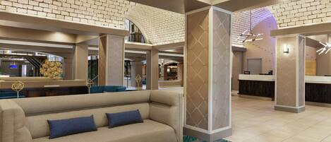 A lobby with a sofa, a reception desk, and a patterned wall.
