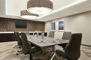 A conference room with a long table, chairs, a flat-screen TV, and artwork on the walls. - Embassy Suites by Hilton Arcadia Pasadena Area (Arcadia)