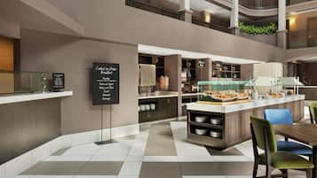 A modern hotel lobby with a central counter, seating area, and a multi-level atrium.