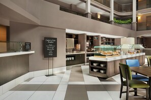 Un lobby de hotel moderno con un mostrador central, zona de estar y un atrio de varios niveles.
