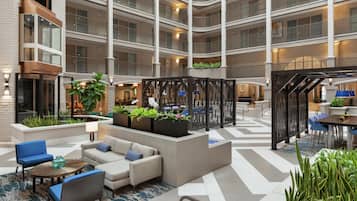 A multi-level hotel atrium with seating areas, plants, and a staircase.