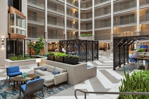 A multi-level hotel atrium with seating areas, plants, and a staircase.