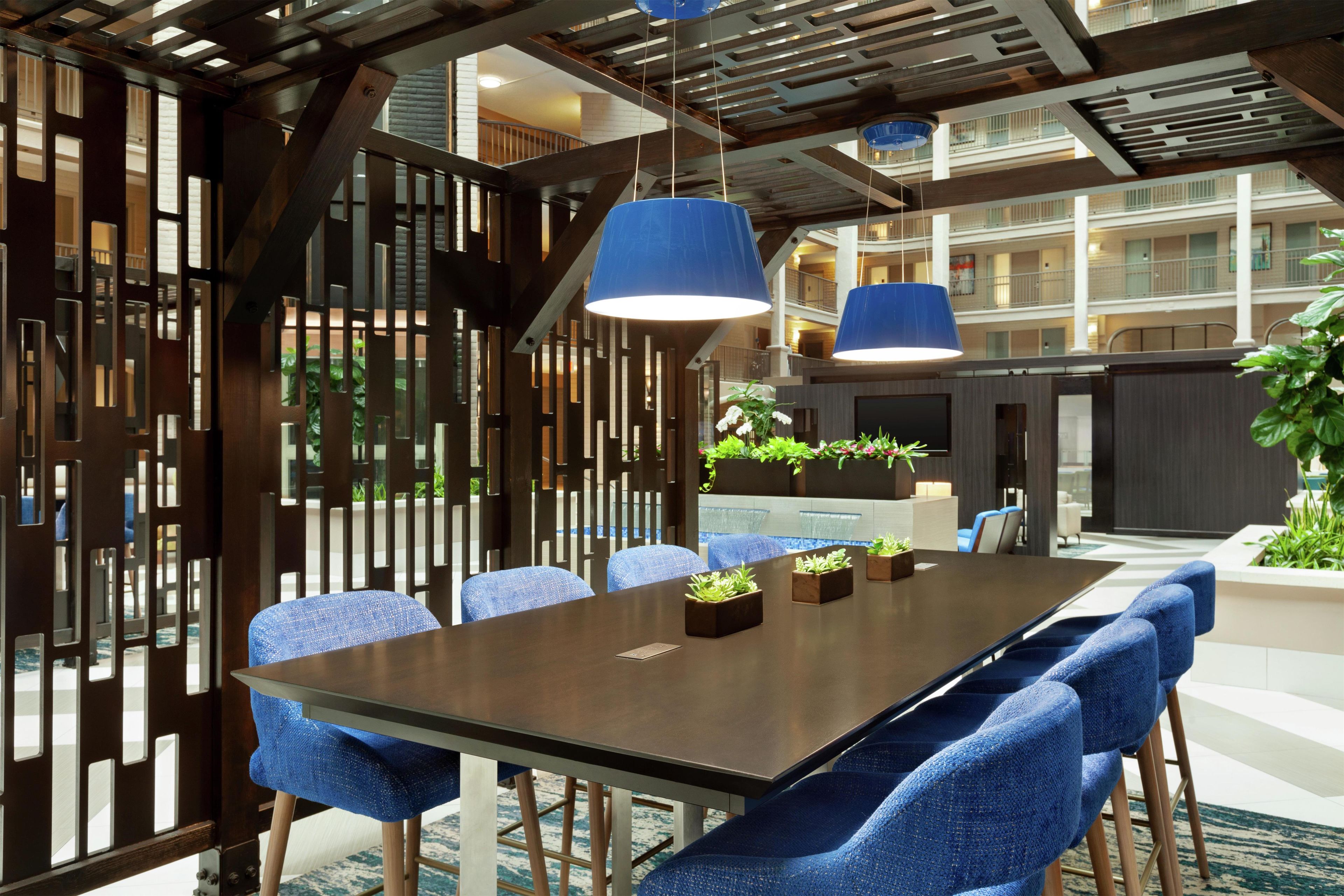 Une salle de conférence avec une longue table, des chaises bleues et des lampes bleues suspendues au plafond.