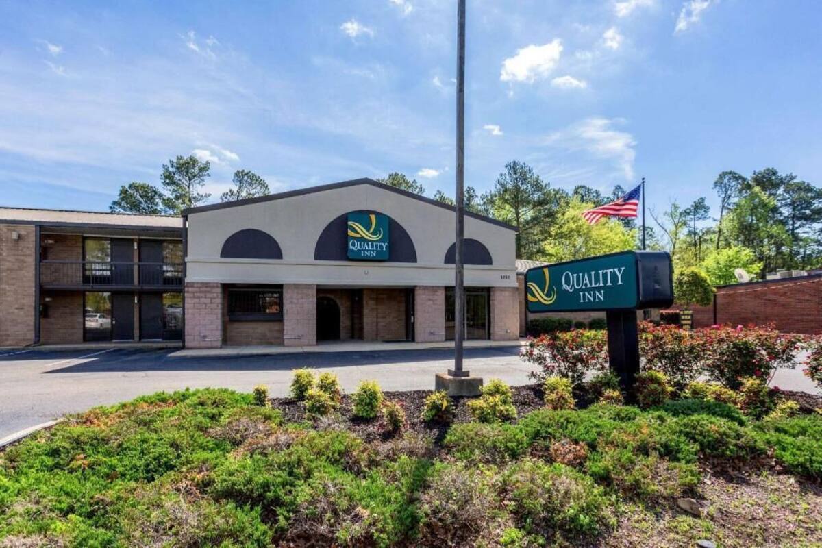 A Quality Inn building with a sign, a flag, and landscaped greenery.
