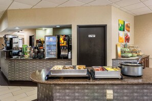 Un'area buffet con diverse opzioni alimentari, una macchina per caffè e un frigorifero.