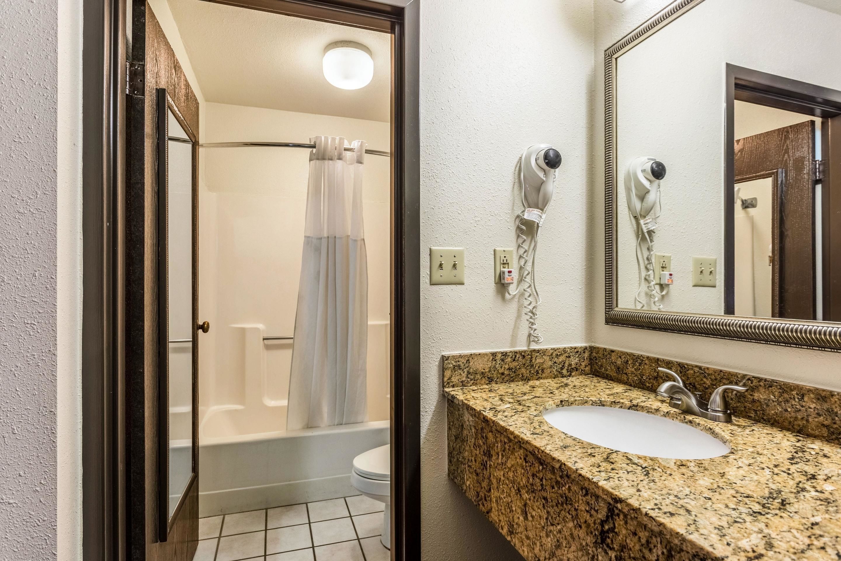 Un baño con ducha, inodoro y lavabo con encimera de granito.