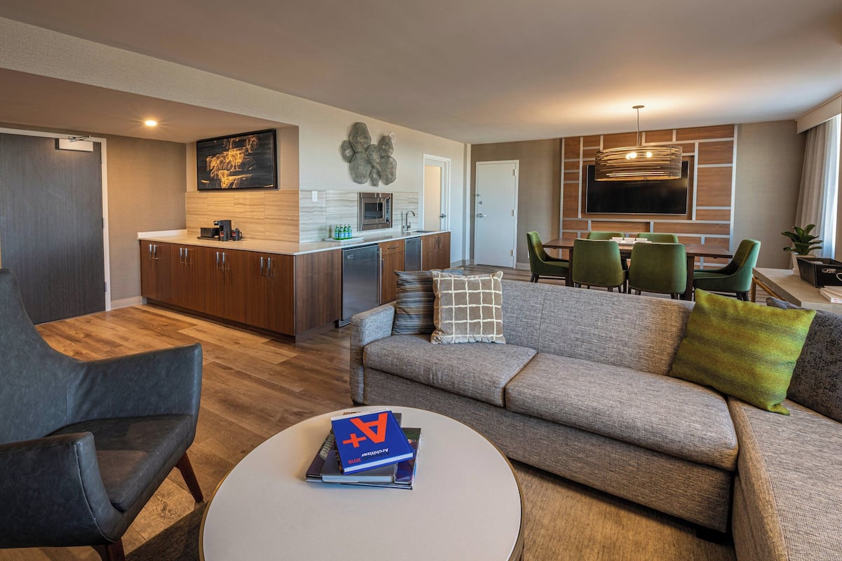A modern living room with a sofa, coffee table, and a dining area with a TV and seating.