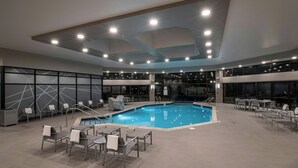 An indoor swimming pool with seating areas and a modern ceiling design. - Marriott Wichita (Wichita)