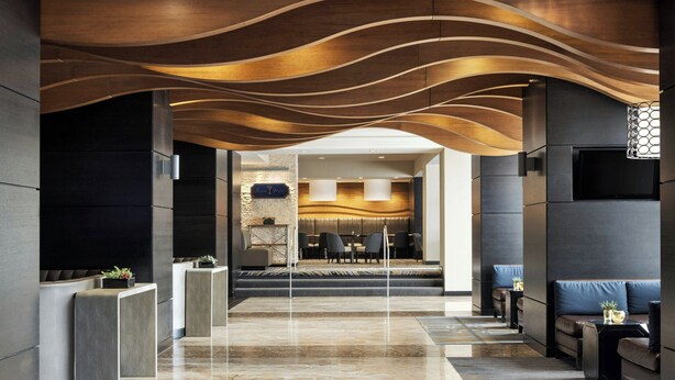 A modern lobby with a marble floor, seating areas, and a reception desk. - Marriott Wichita (Wichita)
