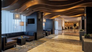 A modern lobby with a curved ceiling, a seating area with sofas and a coffee table, and a patterned rug. - Marriott Wichita (Wichita)