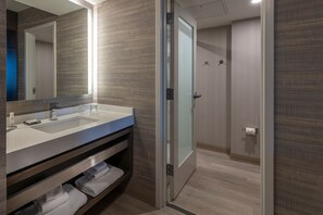 A modern bathroom with a large mirror, a sink, and a shower area.