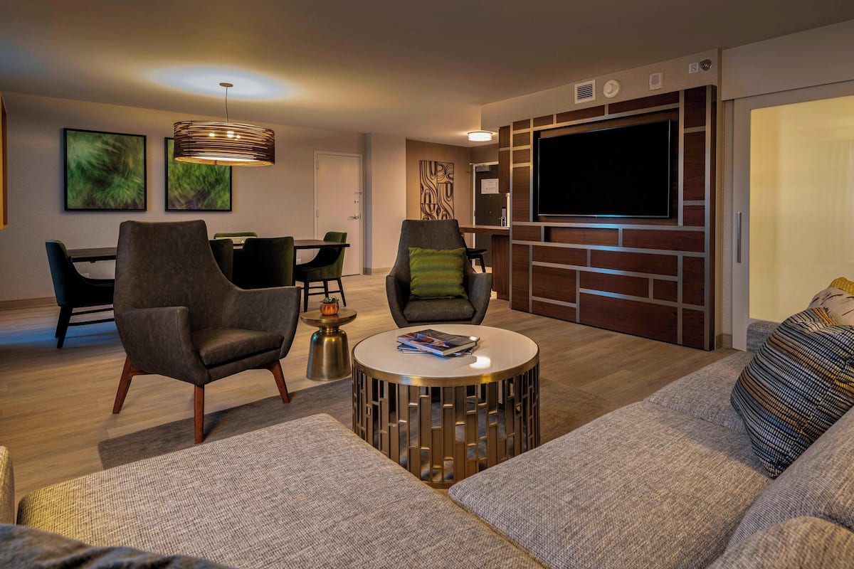 A modern living room with a sofa, armchairs, a coffee table, and a TV wall unit.