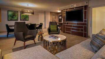 A modern living room with a sofa, armchairs, a coffee table, and a TV wall unit.